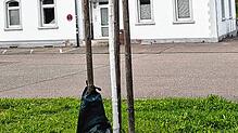 Vor dem Lauchringer Bahnhof hängt ein Bewässerungssack an einem Stützpfahl neben einem noch jungen Baum.