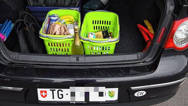 Eine Schweizerin versorgt gerade ihren Einkauf in ihrem Kofferraum.