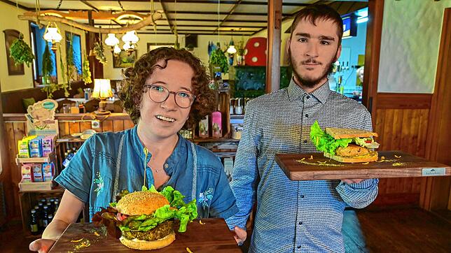 Mia Wagner und Parsival Bauer auf dem Weg, Gästen einen vegangen Burger und ein Schnitzelbrot zu servieren.