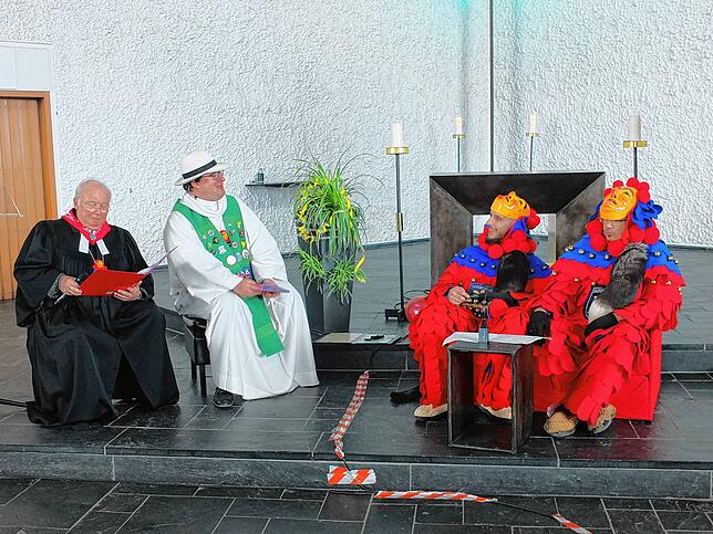 Zwei Eschach-Schnurris klären auf dem roten Sofa die beiden Geistlichen über das Brauchtum der Narren auf.