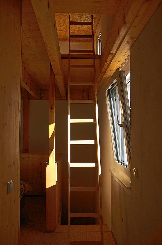 Eine Holzleiter, ein Element aus den Tiny Houses, führt in die Dachgalerie.