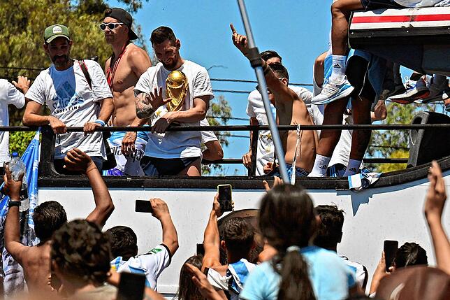 Lionel Messi winkt mit dem WM-Pokal, als er mit der argentinischen Fußballmannschaft in die Stadt fährt.