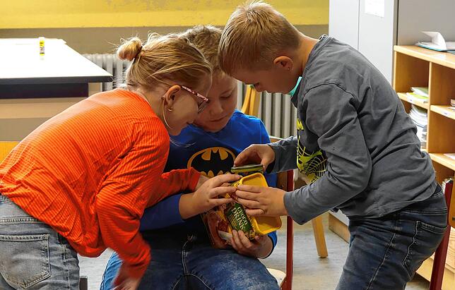 Mit der Lupe erforschen die Kinder die Zutatenliste des Schokodrinks