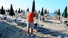 Ein Mann schließt in Ostia (bei Rom) einen Sonnenschirm. Diesen Donnerstag steht der nächste Streik an.  Bilder: Müller-Meiningen (4), dpa