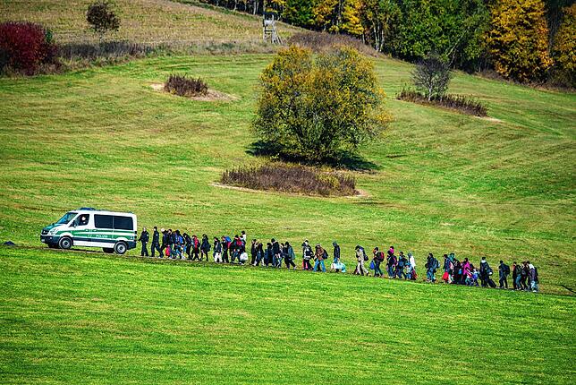 Flüchtlinge gehen 2015 hinter einem Fahrzeug der Bundespolizei her.