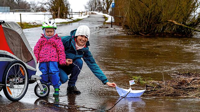 Laura Kunz lässt mit ihrer Tochter Naemi ein Papierschiffchen in den Fluten bei Brigachtal schwimmen.