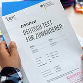 Eine Kursteilnehmerin freut sich über ihr Zertifikat „Deutsch-Test für Zuwanderer“, das sie für die erfolgreiche Teilnahme an einem ...