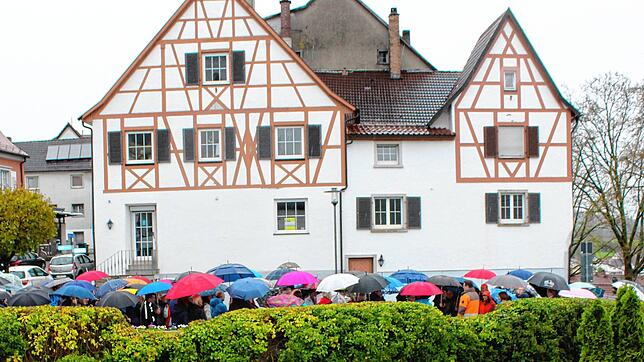 Viele beschirmte Interessierte nahmen bei Regenwetter am Informations-Spaziergang teil. Das Bild zeigt die Gruppe vor dem Strobel-Haus ...