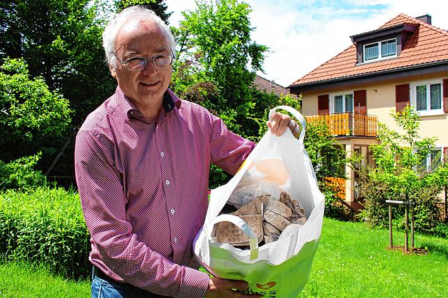 Elmar Mayer in seinem Garten in der Talstraße. Die Tasche ist voller Unrat, den Füchse dorthin geschleppt haben.