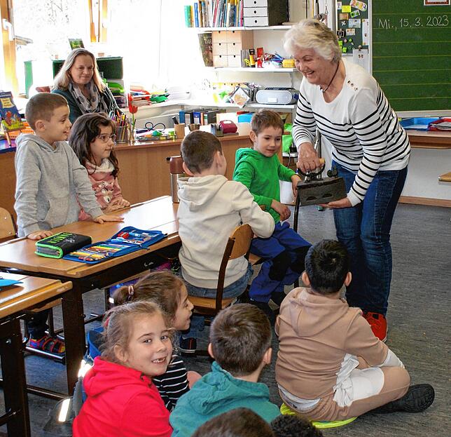 Die Erstklässler der Öflinger Grundschule lassen sich von Mundartdichterin Heidi Zöllner ein altes Glätteisen zeigen. Bild: Schule Öflingen
