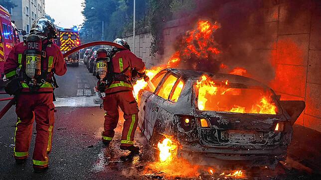 Feuerwehrleute löschen ein brennendes Auto am Rande von Ausschreitungen in Nanterre westlich von Paris.