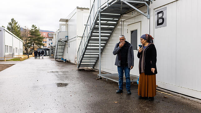 Zwei Bewohner der Landeserstaufnahmeeinrichtung (LEA) in Freiburg stehen vor ihrem Wohncontainer und rauchen. Die Landesregierung ...