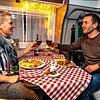 Daniela und Heiko Schütt genießen den Restaurant-Abend in der vertrauten Umgebung ihres Wohnmobils und lassen es sich schmecken.