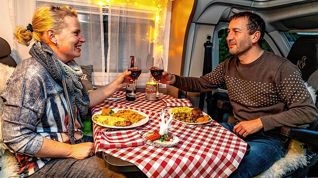Daniela und Heiko Schütt genießen den Restaurant-Abend in der vertrauten Umgebung ihres Wohnmobils und lassen es sich schmecken.
