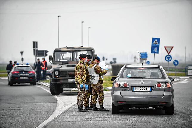 Soldaten mit Atemschutzmaske kontrollieren einen Autofahrer an einer Straßensperre vor der roten Zone von Turano Lodigiano in Norditalien.
