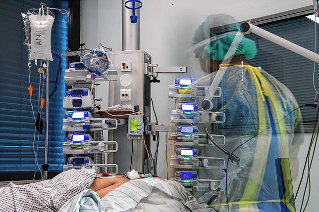Ein Pfleger steht auf der Intensivstation für Corona-Patienten neben einem Patienten, der an einem ECMO-Gerät hängt. Dabei wird die ...