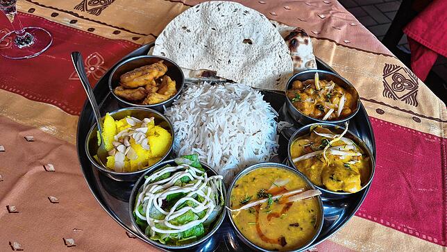 Ein Thali mit Hänchen, Kichererbsen, Salat, Gemüse, Naan-Brot und Basmatireis.