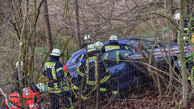 Einsatzkräfte von Feuerwehr und Rotem Kreuz sind mit der Rettung der Beifahrerin beschäftigt. Aufgrund der Hanglage des Fahrzeugs ...