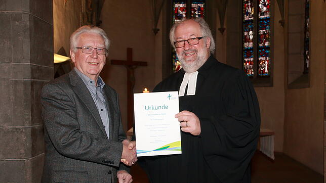 Pfarrer Peter Krech (rechts) gratuliert Harald Apelt zur Verleihung der goldenen Ehrennadel der evangelischen Landeskirche Baden und ...