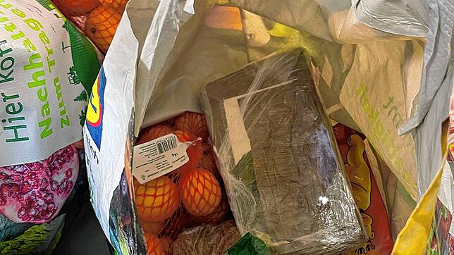 In einer Einkaufstüte kommen unter einem Netz mit Orangen zwei Päckchen Kokain zum Vorschein.