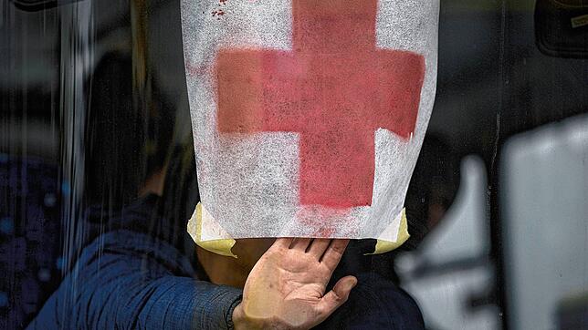 Ein Mann drückt ein Papier mit einem roten Kreuz gegen die Windschutzscheibe eines Busses, während Zivilisten aus Irpin evakuiert werden.