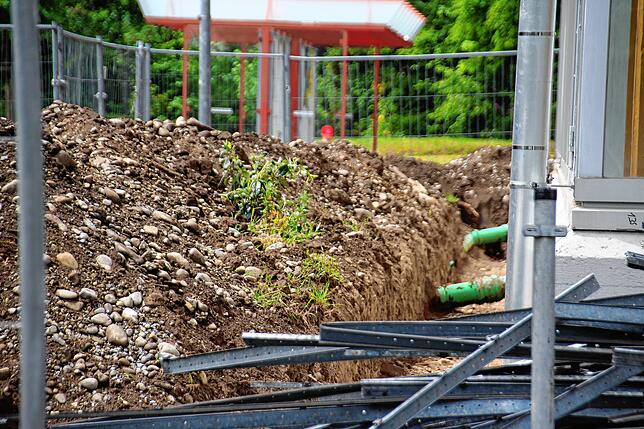 Vor dem Hallenbad sind Erdhaufen zu sehen. Für die neue Glasfassade haben schon Erdarbeiten stattgefunden.