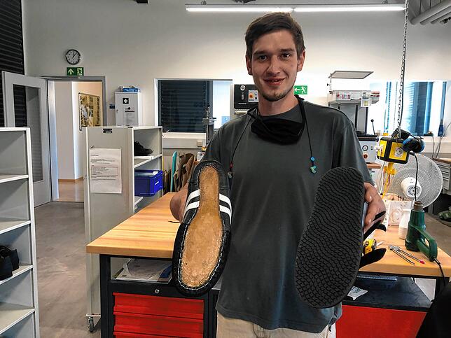 Iacubino zeigt einen Schuh ohne und einen mit neuer Sohle.