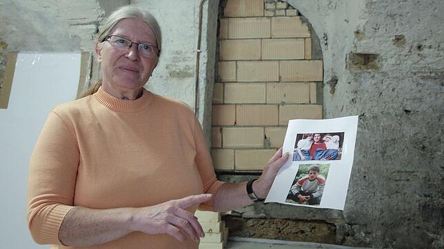 Gisela Rode steht vor der Mauer, hinter der sie Spuren eines Verbrechens vermutet, mit den Bildern ihres vermissten Neffen, Joachim ...