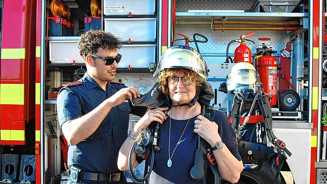 Ganz schön schwer: Grünen-Stadträtin Annette Hufschmidt bekommt Teile einer Feuerwehrausrüstung für den Atemschutz angelegt.