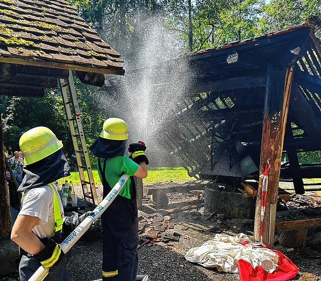 Löscheinsatz an der Grillstelle: Zwei Frauen der Feuerwehr Markdorf richten den Strahl ins Gebälk der Überdachung.