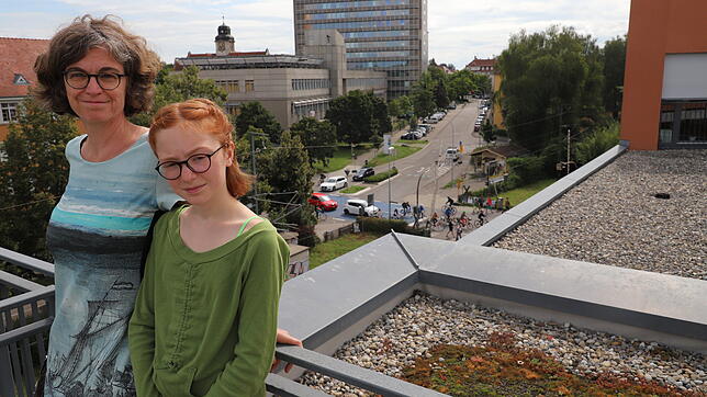 Claudia Diehl und ihre Tochter Pia Preisendörfer auf ihrer Dachterrasse. Im Hintergrund ist der Bahnübergang auf der Fahrradstraße zu sehen.