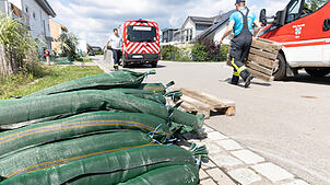 Mitglieder der Feuerwehr legen Paletten aus, auf die die Anwohner ihre nicht mehr benötigten Sandsäcke deponieren können.
