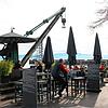 Um den Hafenkran herum sind Stühle und Tische eines Restaurants aufgestellt. Im Hintergrund ist der Moleturm zu sehen.