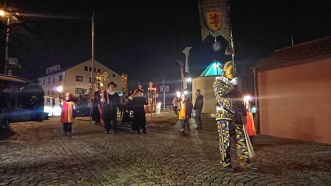 Standartenträger, Bürgermeister und Gemeinderat marschieren an der Spitze der Tschättermusik auf das Waldtor zu.