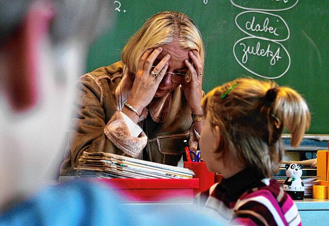 Eine Lehrerin sitzt verzweifelt vor ihrer Klasse: Szenen wie diese sind durch die Corona-Pandemie an Schulen häufiger geworden.