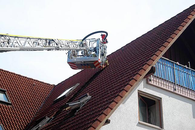 Zur Kontrolle werden Ziegel vom Dach über dem Brandherd entfernt, um mögliche Schwelbrände nicht zu übersehen.