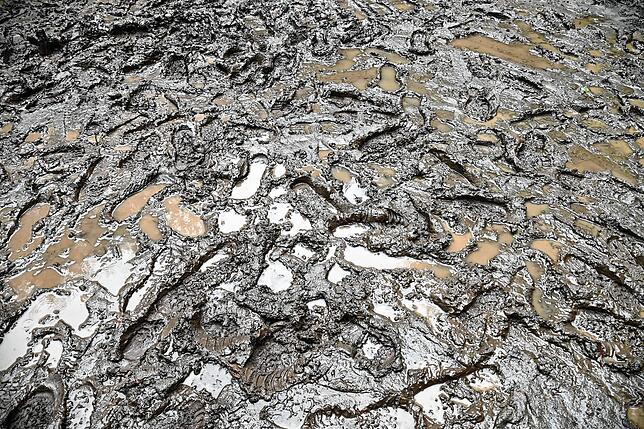 Matsch und Fußspuren zeigen, wie sich das Wetter auf die Baustelle auswirkt. Laufen ist auf dem abschüssigen Stück alles andere als einfach.