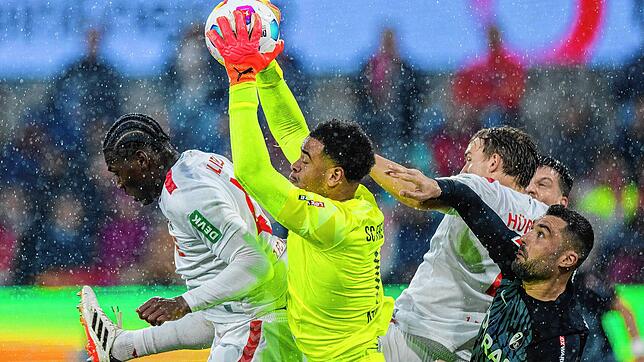 Freiburgs Torwart Noah Atubolu kommt vor Kölns Faride Alidou (l) an den Ball.
