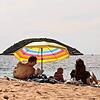 Eine Familie liegt unter einem Sonnenschirm am Strand von Mallorca. Nicht nur bei Fernreisen, sondern auch innerhalb der EU gibt es ...