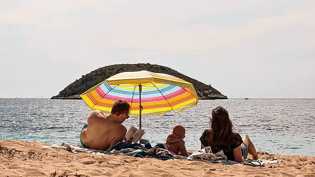 Eine Familie liegt unter einem Sonnenschirm am Strand von Mallorca. Nicht nur bei Fernreisen, sondern auch innerhalb der EU gibt es ...