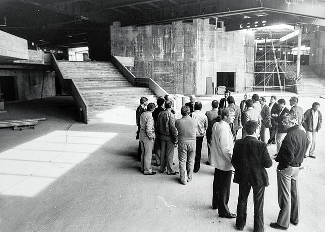 Besucher stehen im Rohbau vor der Treppe, die vom Eingang hinab zum großen Foyer des Hugo-Eckener-Saals führt.