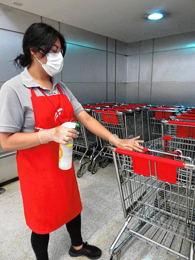 Szene im Supermarkt: Einkaufswagen werden nach Gebrauch desinfiziert