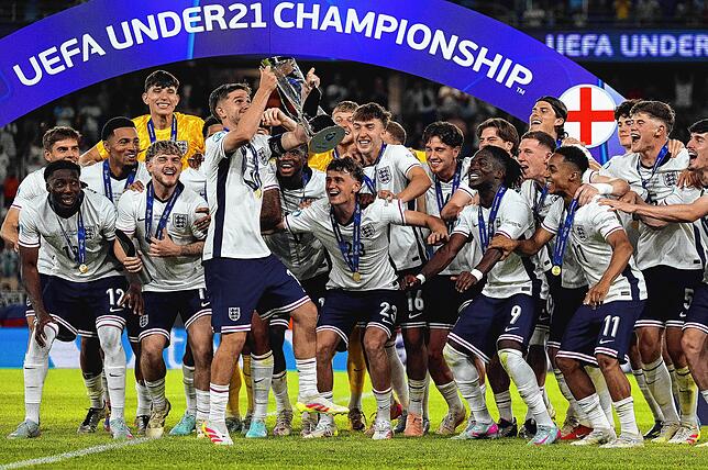 Englands Kapitän James McAtee (Mitte l) hebt den Pokal nach dem Sieg, während seine Teamkollegen jubeln.