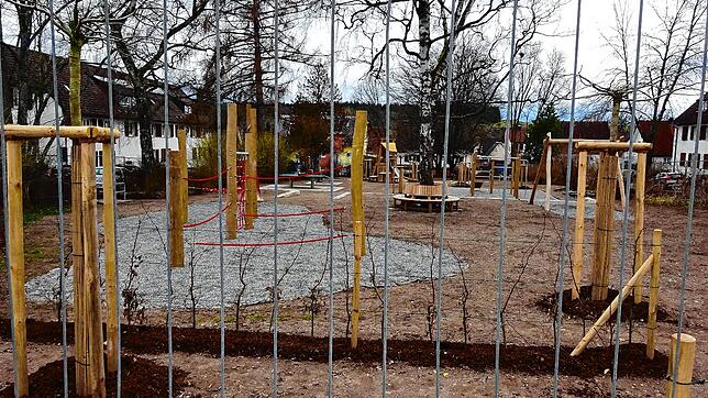 Ein Spielplatz hinter Gittern. Aber nur solange, bis der noch nicht gewachsene Rasen zwischen den Spielgeräten Grün signalisiert.