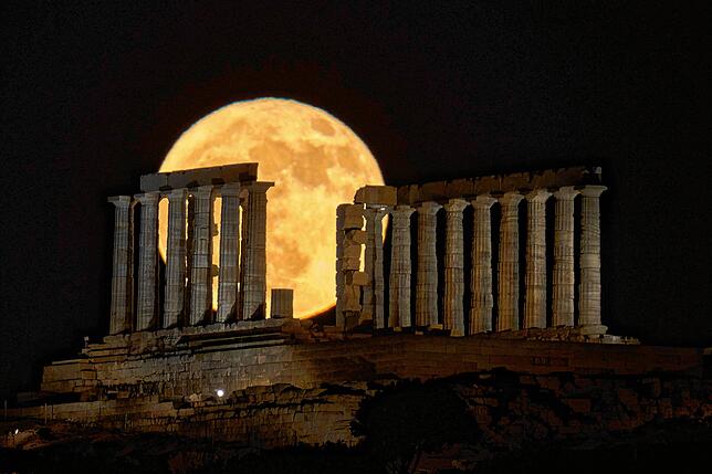 Der Erdbeermond zeigt sich hinter dem antiken Poseidontempel am Kap Sounion in Griechenland.