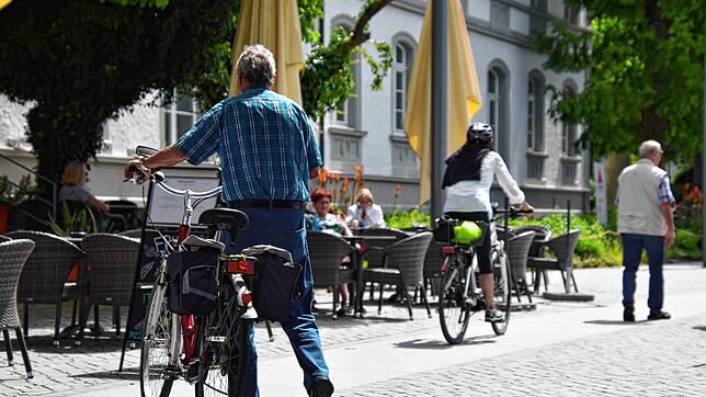 Während der eine Radfahrer sich an das Fahrverbot auf der Promenade hält, tut es die ihm vorausfahrende Dame nicht.
