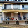 Das Wohnhaus, in dem einige Bauarbeiter unter Quarantäne stehen. Ein junger Mann sitzt auf dem Balkon und raucht.