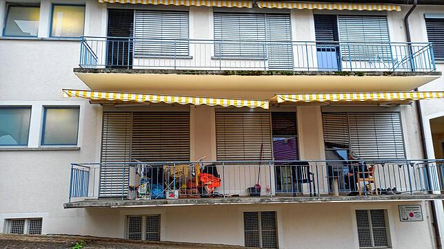 Das Wohnhaus, in dem einige Bauarbeiter unter Quarantäne stehen. Ein junger Mann sitzt auf dem Balkon und raucht.