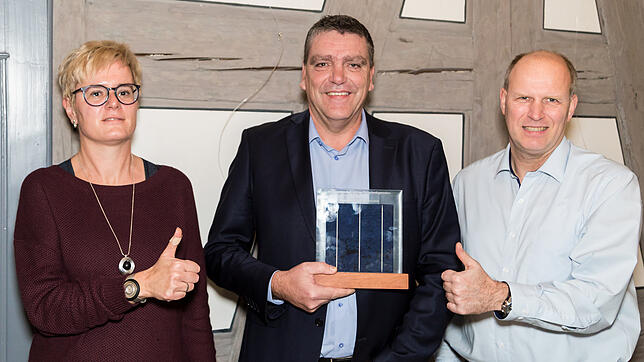 Eine Auszeichnung, auf die Öhningen stolz sein kann: Bürgermeister Andreas Schmid (Mitte) hält eine Stele, die ein Photovoltaik-Modul ...