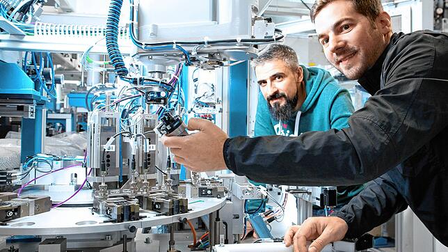 Zwei Mitarbeiter von Eto Magnetic aus Stockach nehmen eine Maschine zur Serienfertigung von Elektrobauteilen in Betrieb.